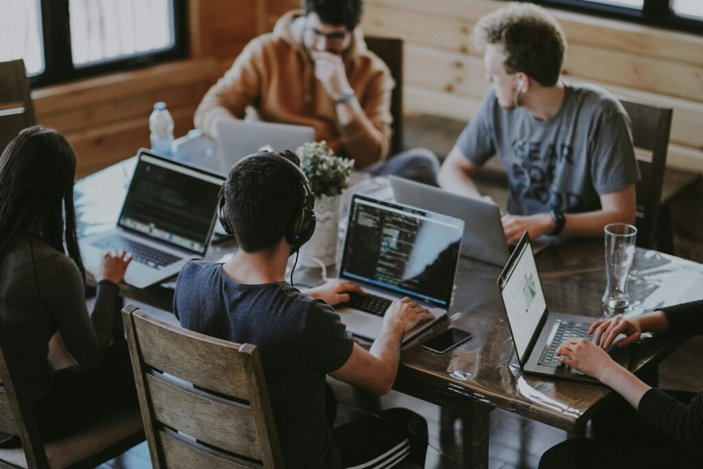 Small business team reviewing shared data on laptops around a table